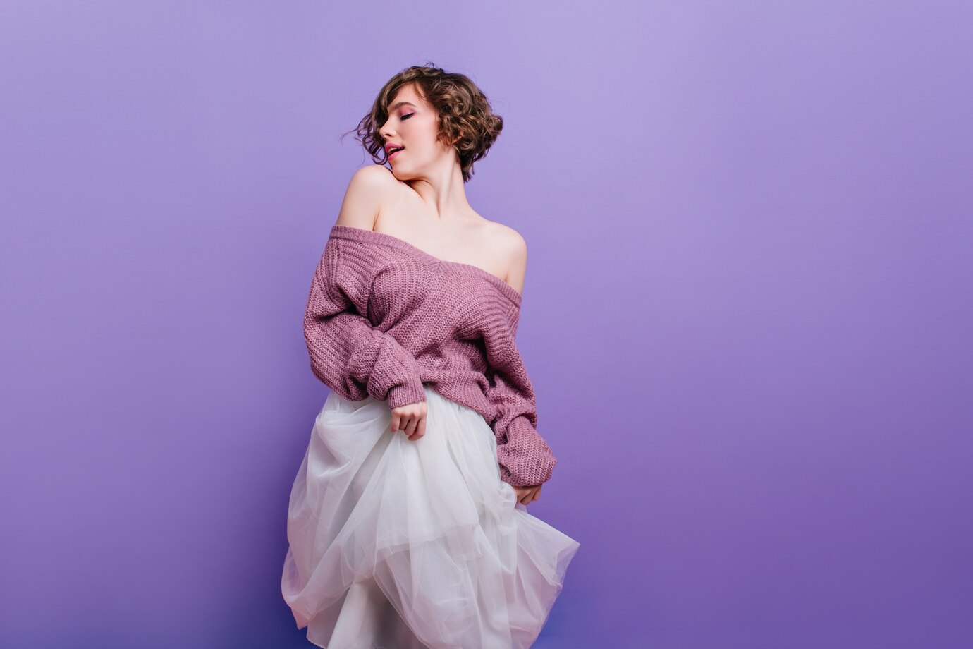 Cheerful brown haired female model sweater having fun indoor photoshoot pretty brunette curly lady playing with lush white skirt 197531 7995